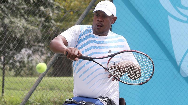 a male wheelchair tennis player takes a shot