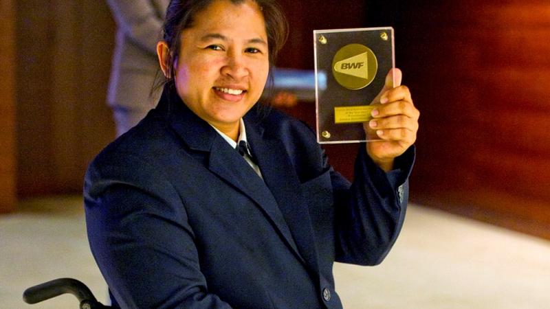 a female Para badminton player holds up an award