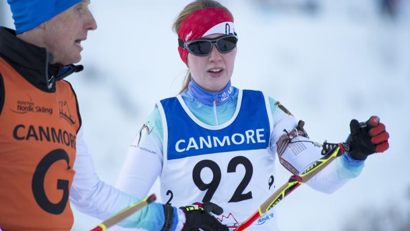 Two people talking, one on the right is competing in Para Nordic Skiing