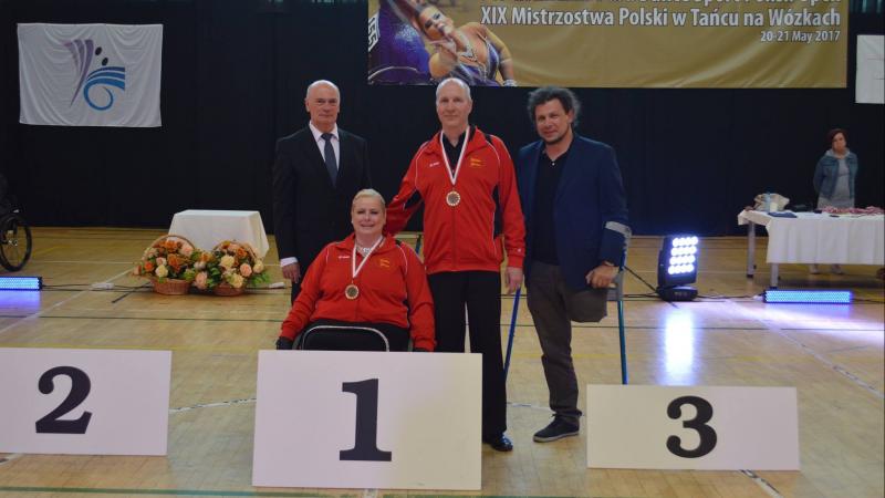 Female dancer in wheelchair poses for photo with standing partner and two other officials
