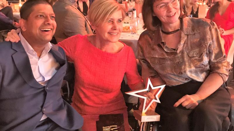 a man and two women smiling with a trophy