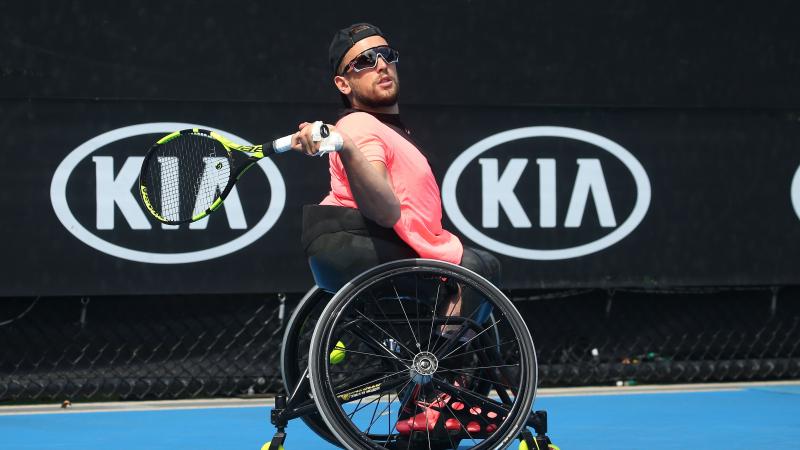 a male quad tennis player takes a shot