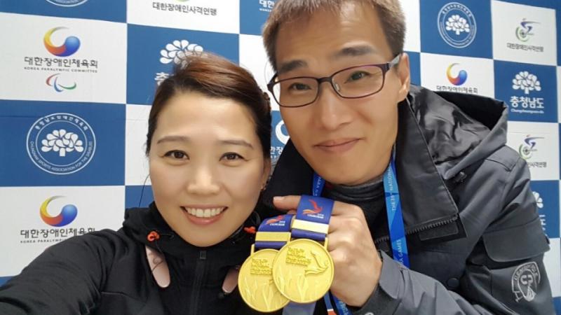 a man and a woman hold up a medal