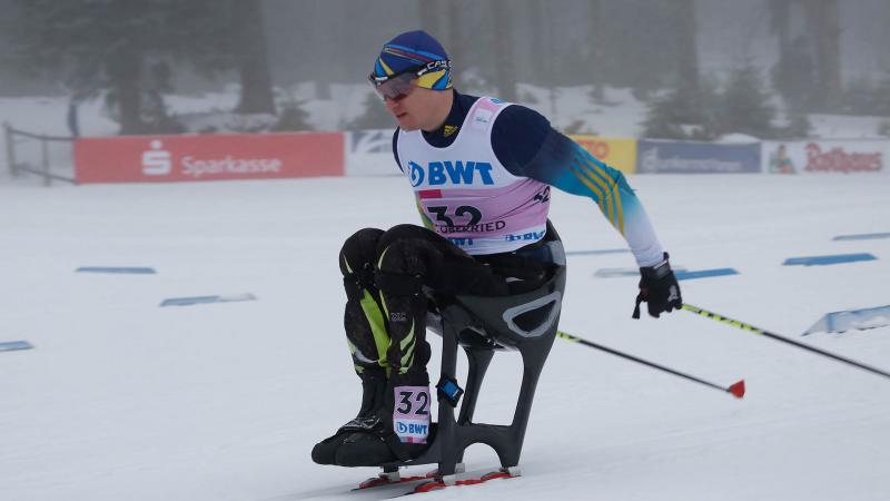 a male sit skier ploughs through the snow