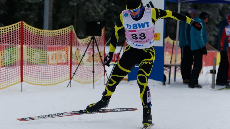 A male Para Nordic skier sprints towards the finish line