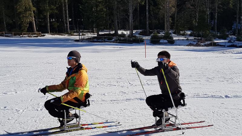two male sit skiers on the snow