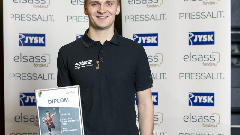 a male Para athlete holds up a certificate