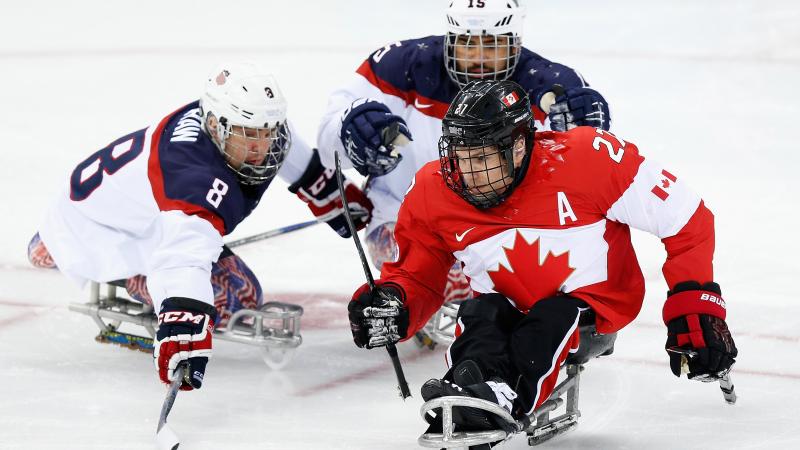 three male Para ice hockey players clash on the ice