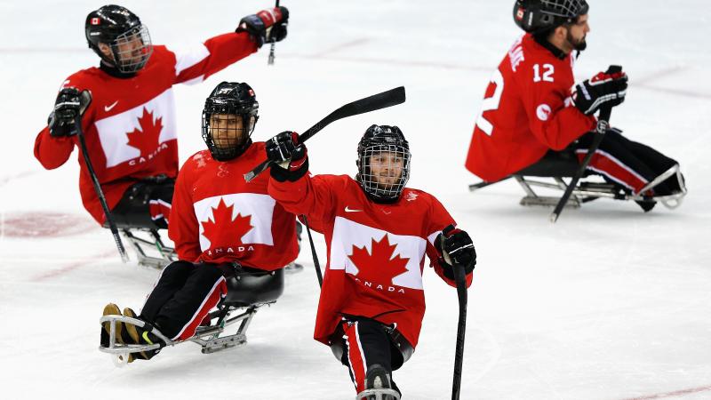 four male Para ice hockey players celebrate on the ice