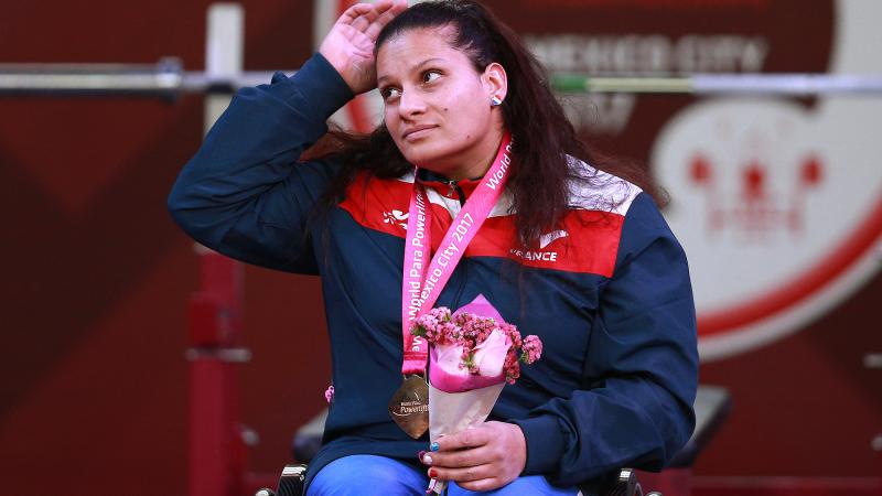 a female powerlifter on the podium with her gold medal