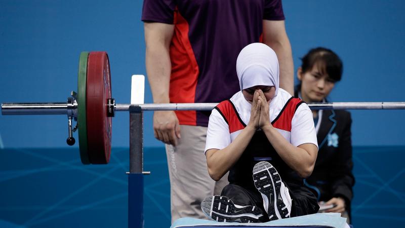 A female powerlifter prays on the bench before a lift