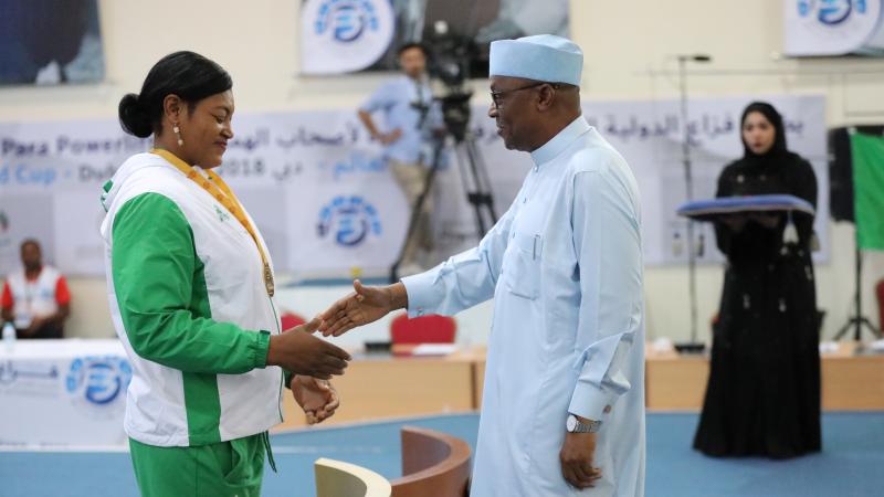 a female powerlifter shakes hands with a sheikh