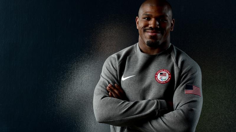 a male judoka smiles with his arms folded