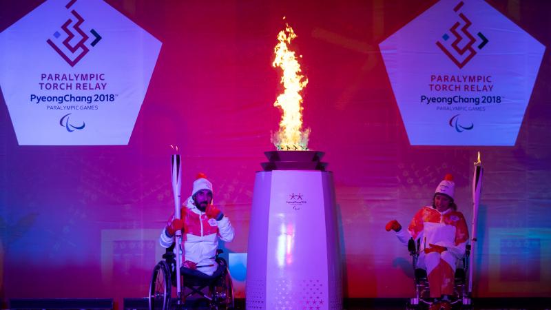 two athletes light a flame