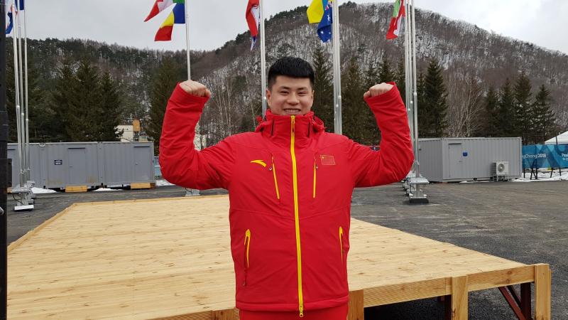 a male Para snowboarder gives a thumbs up