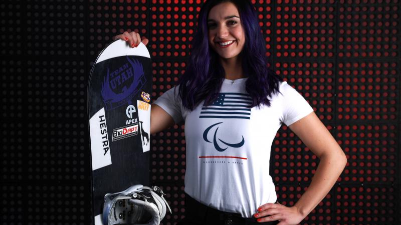 a female Para snowboarder poses with her board