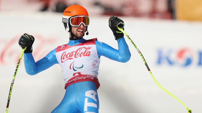 a male Para alpine skier celebrates on the slope