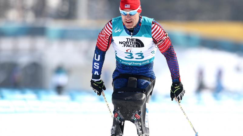 a male Para sit skier crosses the finish line