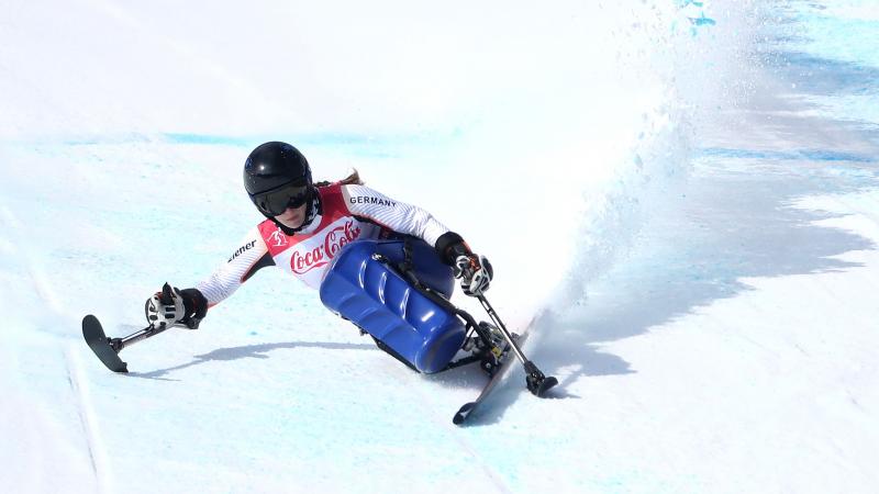 a female sit skier rounds a gate