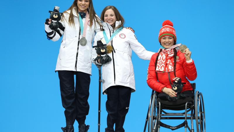 three female sit skiers on the podium with their medals