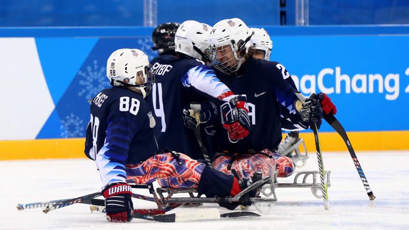 a group of Para ice hockey players celebrating a goal