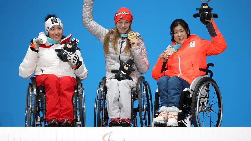 three female sit skiers on the podium with their medals