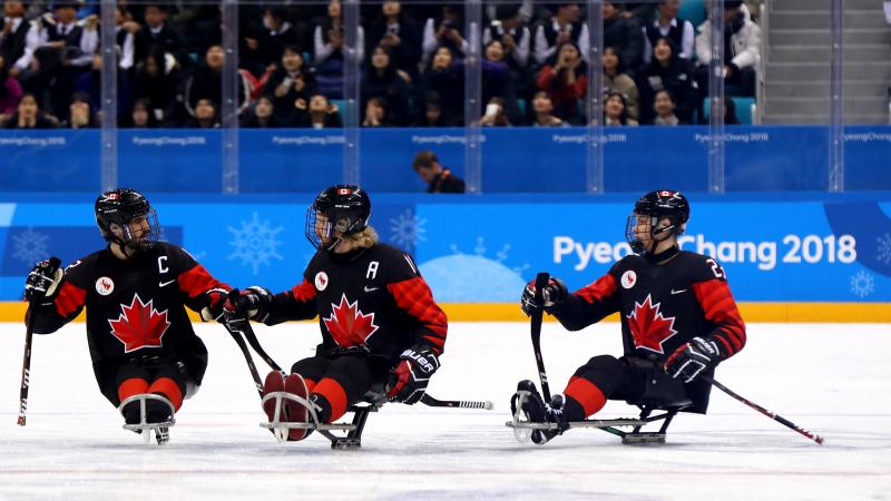 a group of Para ice hockey players celebrate on the ice