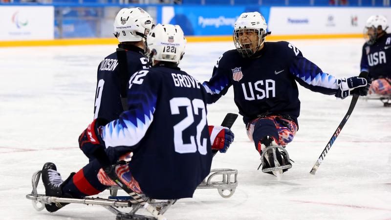 Para ice hockey players celebrate on the ice