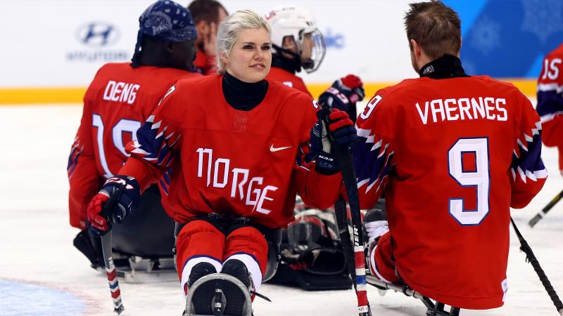 a female Para ice hockey player with her teammates on the ice