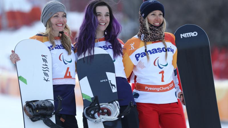 three female snowboarders on a podium