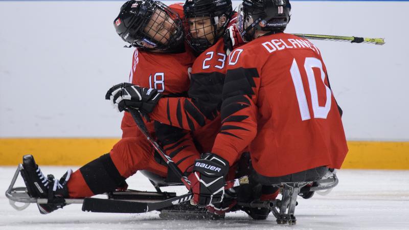 Three Para ice hockey players celebrating a goal