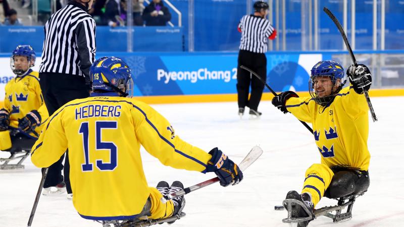 two Para ice hockey players celebrate a goal