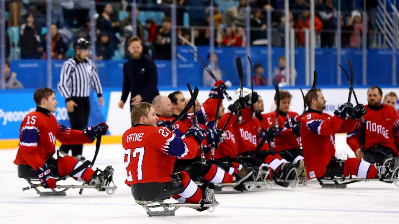 a group of Para ice hockey players celebrating on the ice
