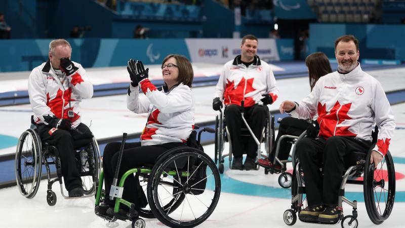 a wheelchair curling team celebrates on the ice