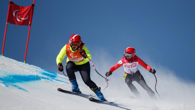 a female vision impaired skier and her guide take on a gate