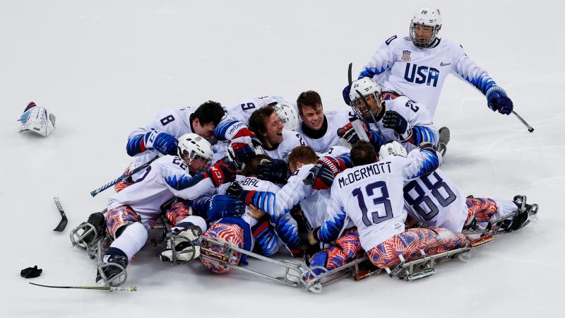 a group of Para ice hockey players celebrate on the ice