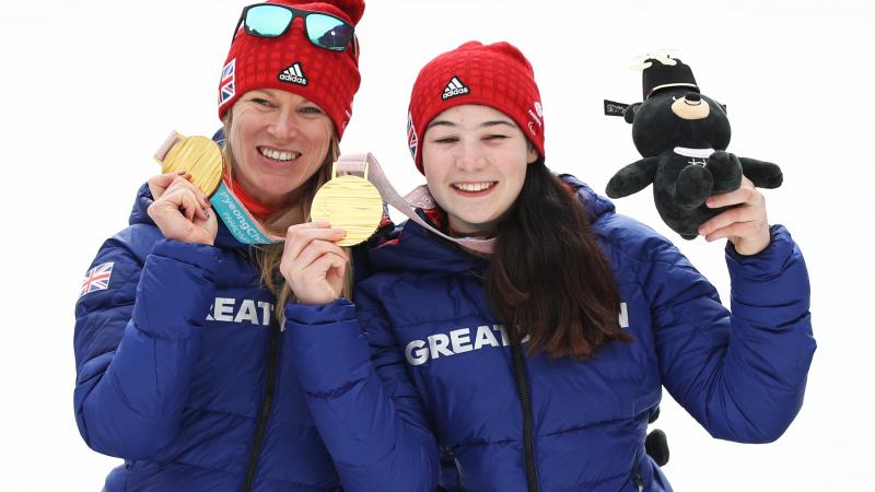two female alpine skiers with gold medals on the podium