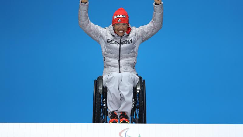 a wheelchair athlete raises her arms on the podium