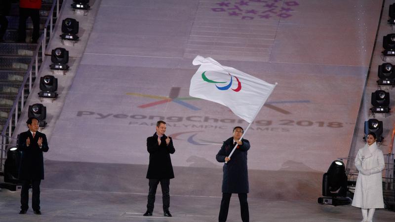 Three men standing, one of them holding a flag