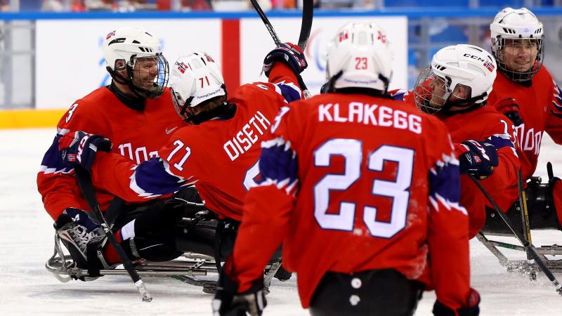 a group of Para ice hockey players celebrate a goal