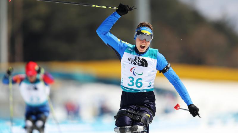 a male Para sit skier crosses the line and celebrates