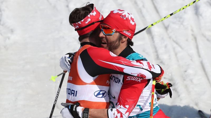 a visually impaired skier and his guide hug on the finish line