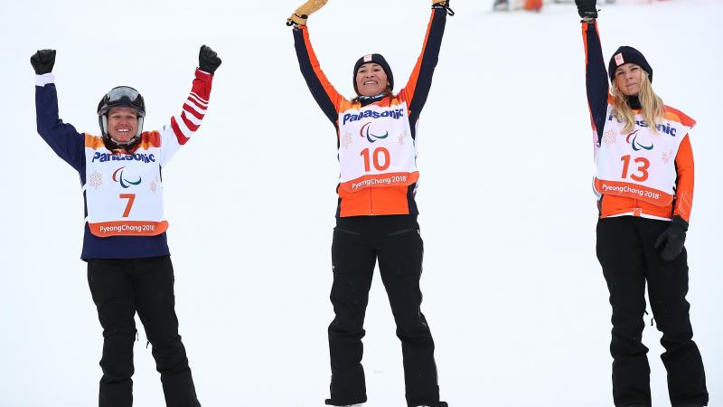 three female snowboarders jump in the air 