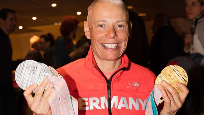 a female athlete holds up her six Paralympic medals