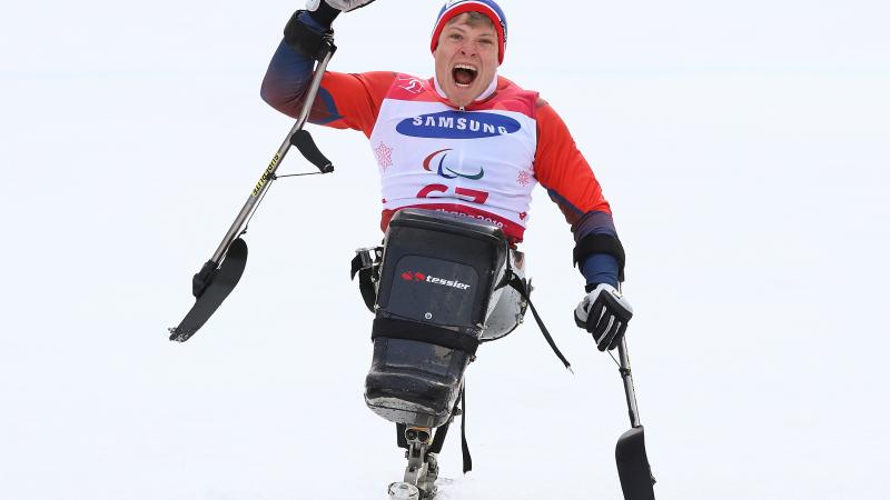 a male sit skier punches the air in celebration