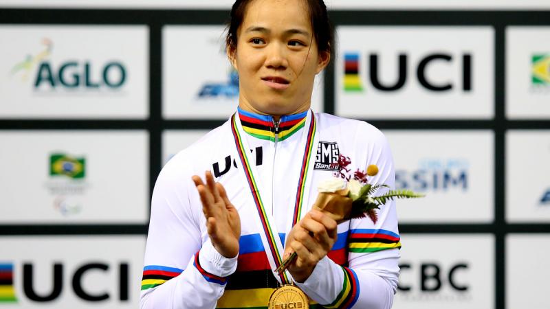 A female Para cyclist applauds on the podium