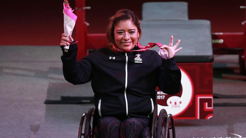 a female powerlifter holds up her gold medal