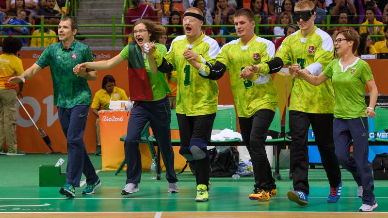 a group of goalball players link arms in celebration