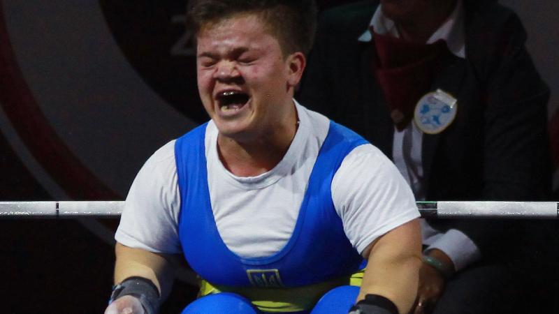 a female powerlifter clenches her fists on the bench