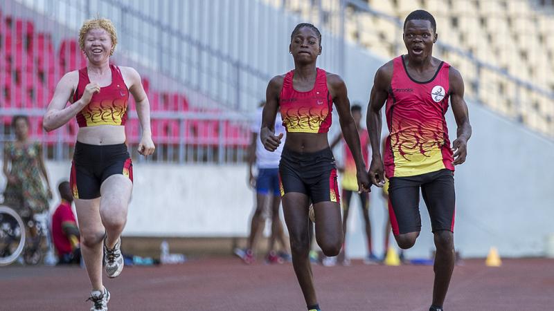 Three athletes running on a track